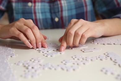 Young woman playing with puzzles at table, closeup Photo of Young woman playing with puzzles at table, closeup