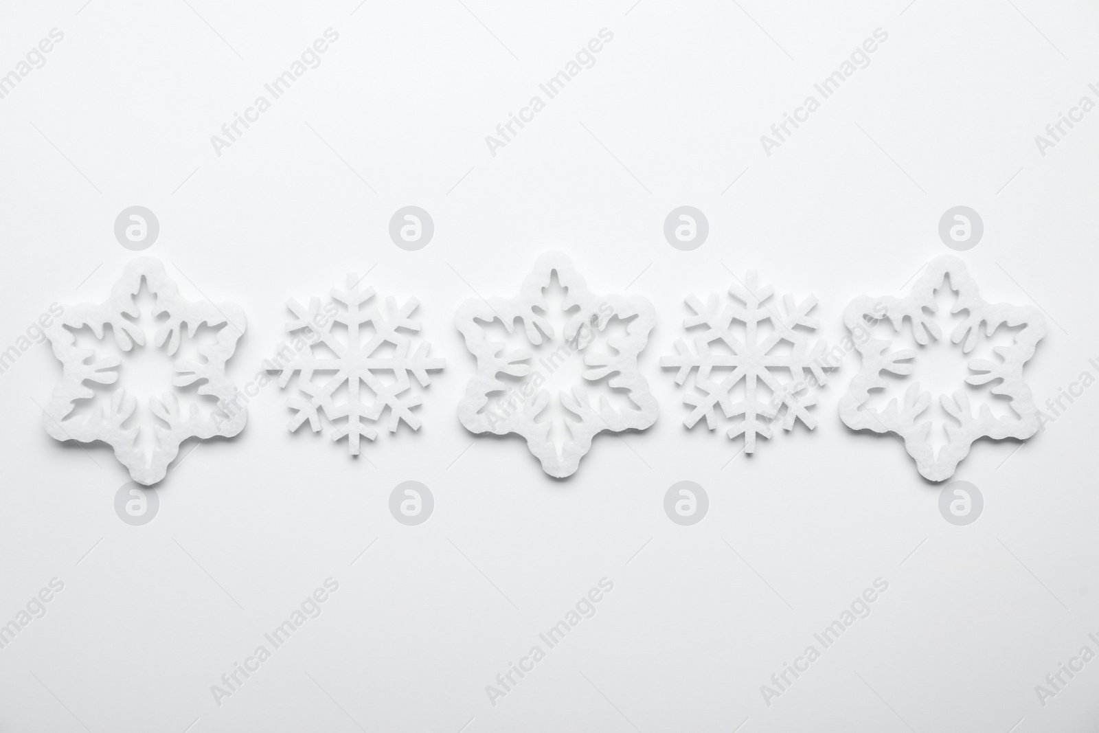 Beautiful decorative snowflakes on white background, flat lay Photo of Beautiful decorative snowflakes on white background, flat lay