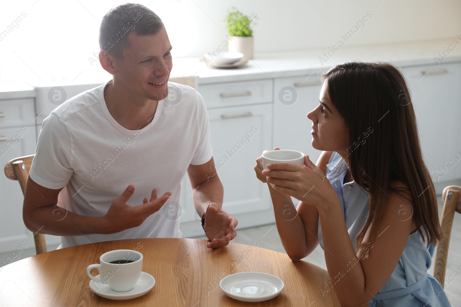 Man and woman talking while drinking tea at table in kitchen Photo of Man and woman talking while drinking tea at table in kitchen