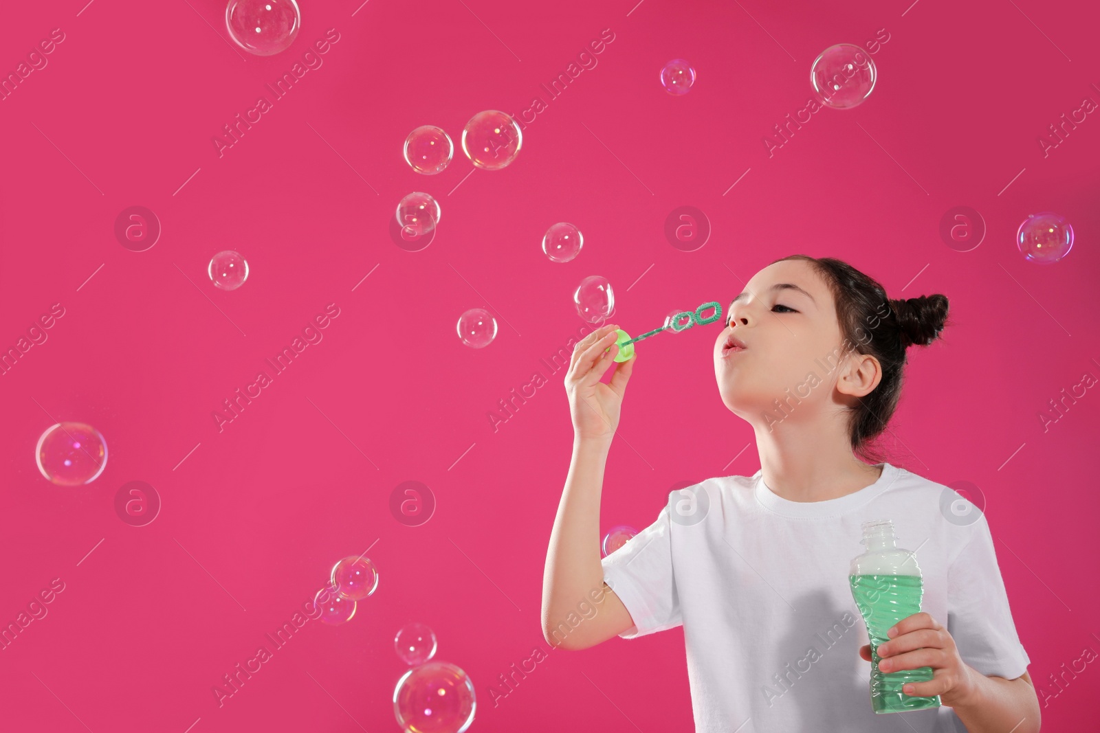 Little girl blowing soap bubbles on pink background, space for text Photo of Little girl blowing soap bubbles on pink background, space for text