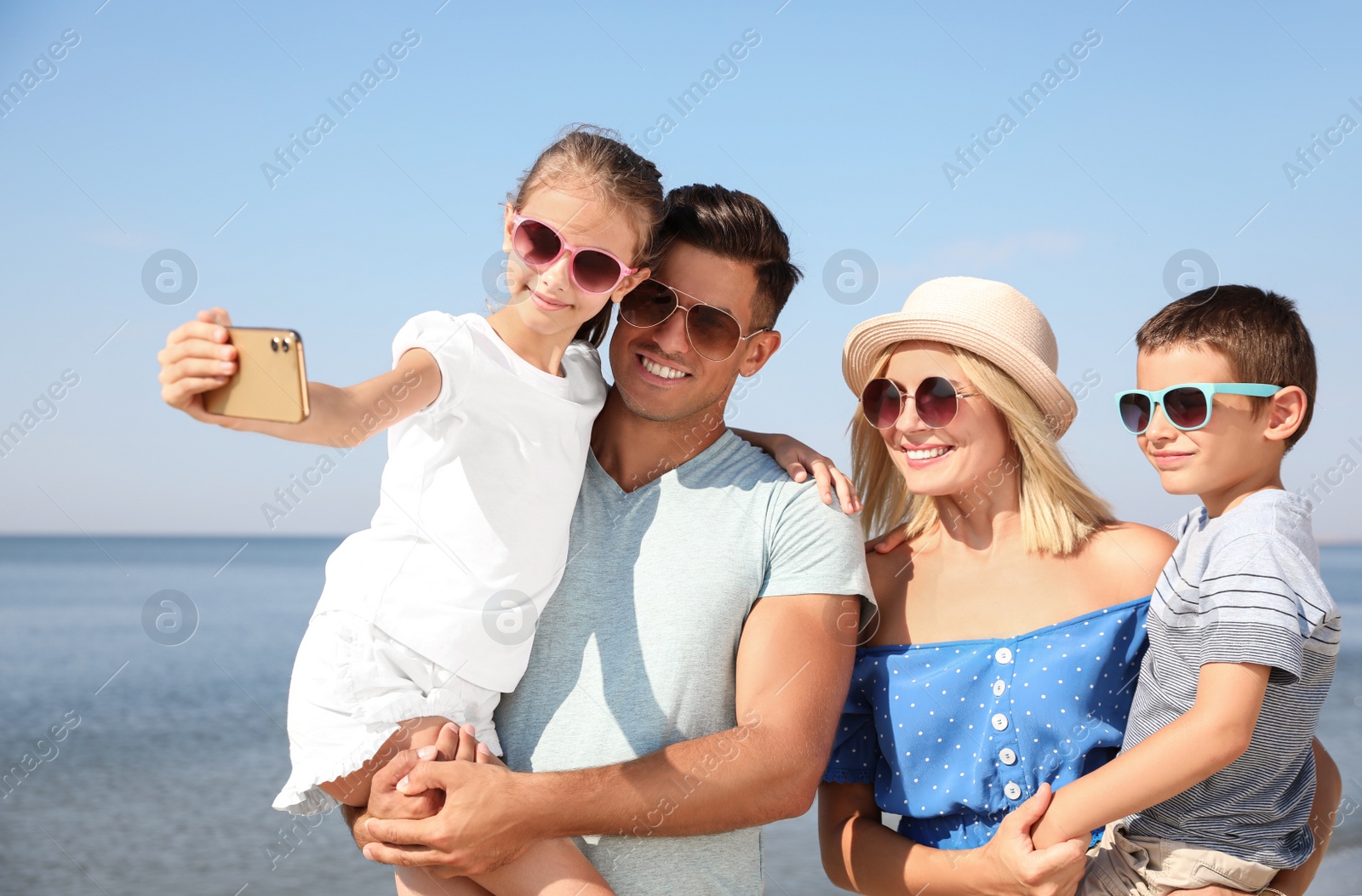 Happy family taking selfie at beach on sunny day Photo of Happy family taking selfie at beach on sunny day