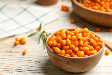 Fresh ripe sea buckthorn in bowl on white wooden table. Space for text Photo of Fresh ripe sea buckthorn in bowl on white wooden table. Space for text