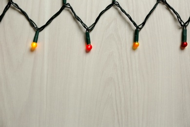 Beautiful glowing Christmas lights on white wooden background, top view. Space for text Photo of Beautiful glowing Christmas lights on white wooden background, top view. Space for text