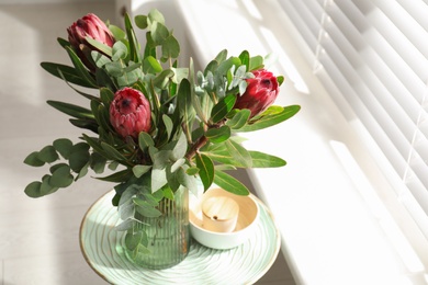 Vase with bouquet of beautiful Protea flowers on table indoors Photo of Vase with bouquet of beautiful Protea flowers on table indoors
