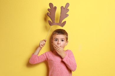 Cute little boy with reindeer antlers prop on yellow background. Christmas celebration Image of Cute little boy with reindeer antlers prop on yellow background. Christmas celebration