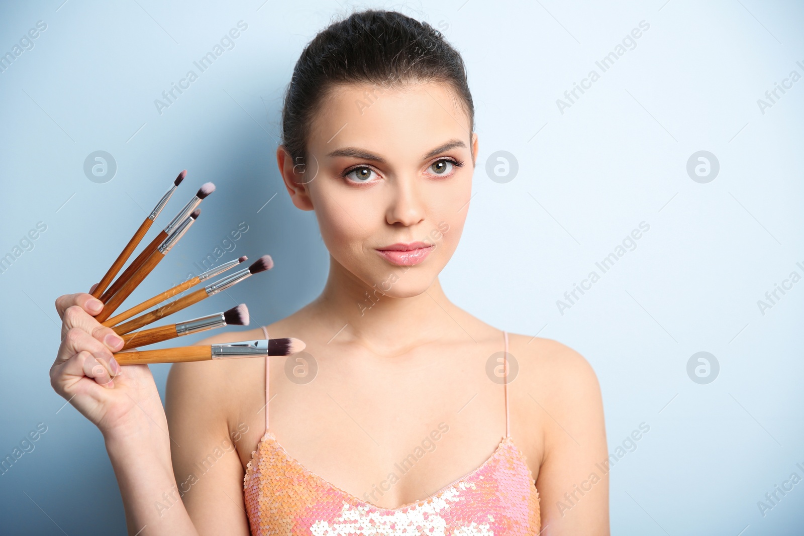 Young woman with makeup brushes on color background. Professional cosmetic products Photo of Young woman with makeup brushes on color background. Professional cosmetic products
