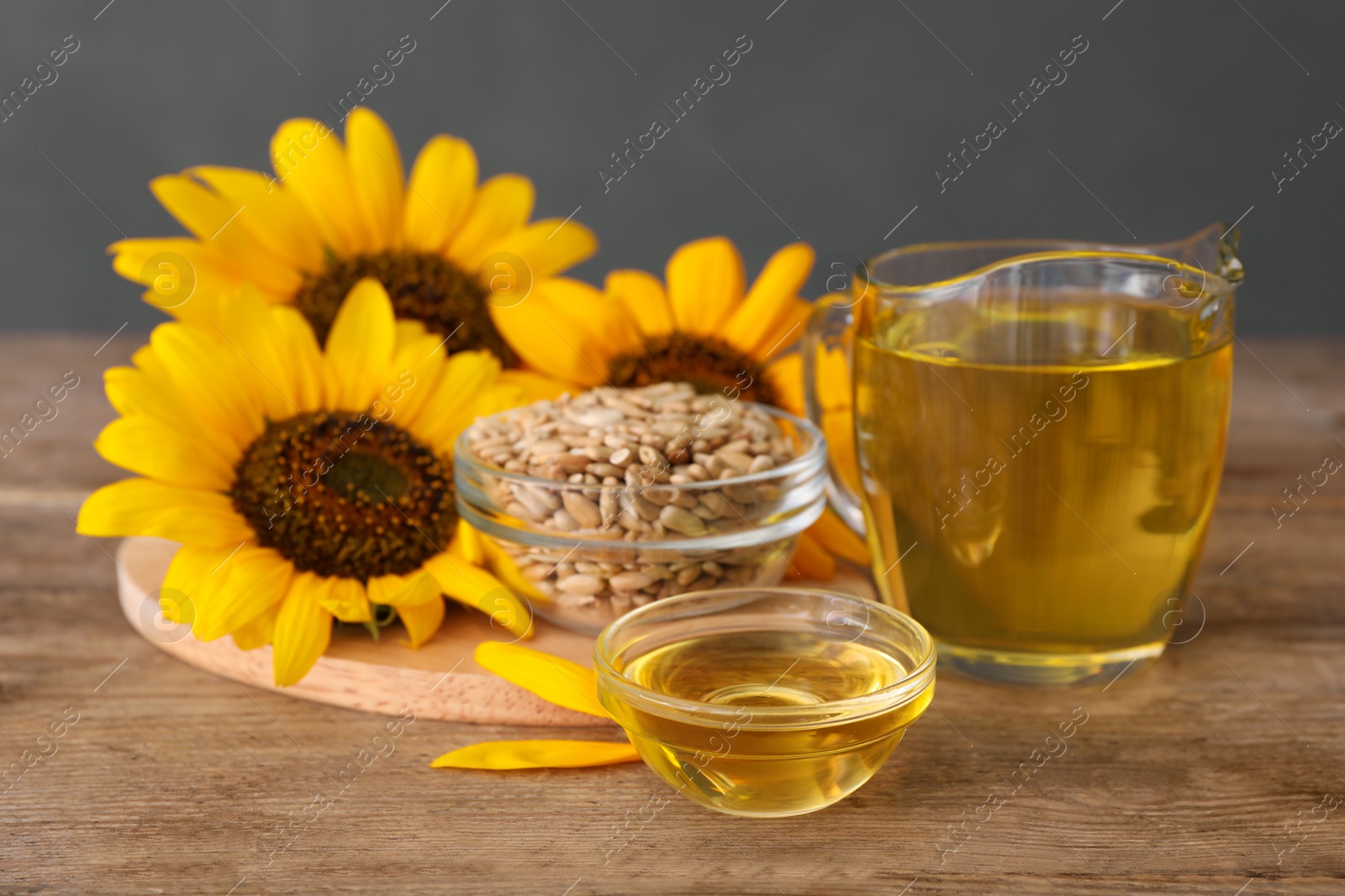 Sunflowers, oil and seeds on wooden table Photo of Sunflowers, oil and seeds on wooden table