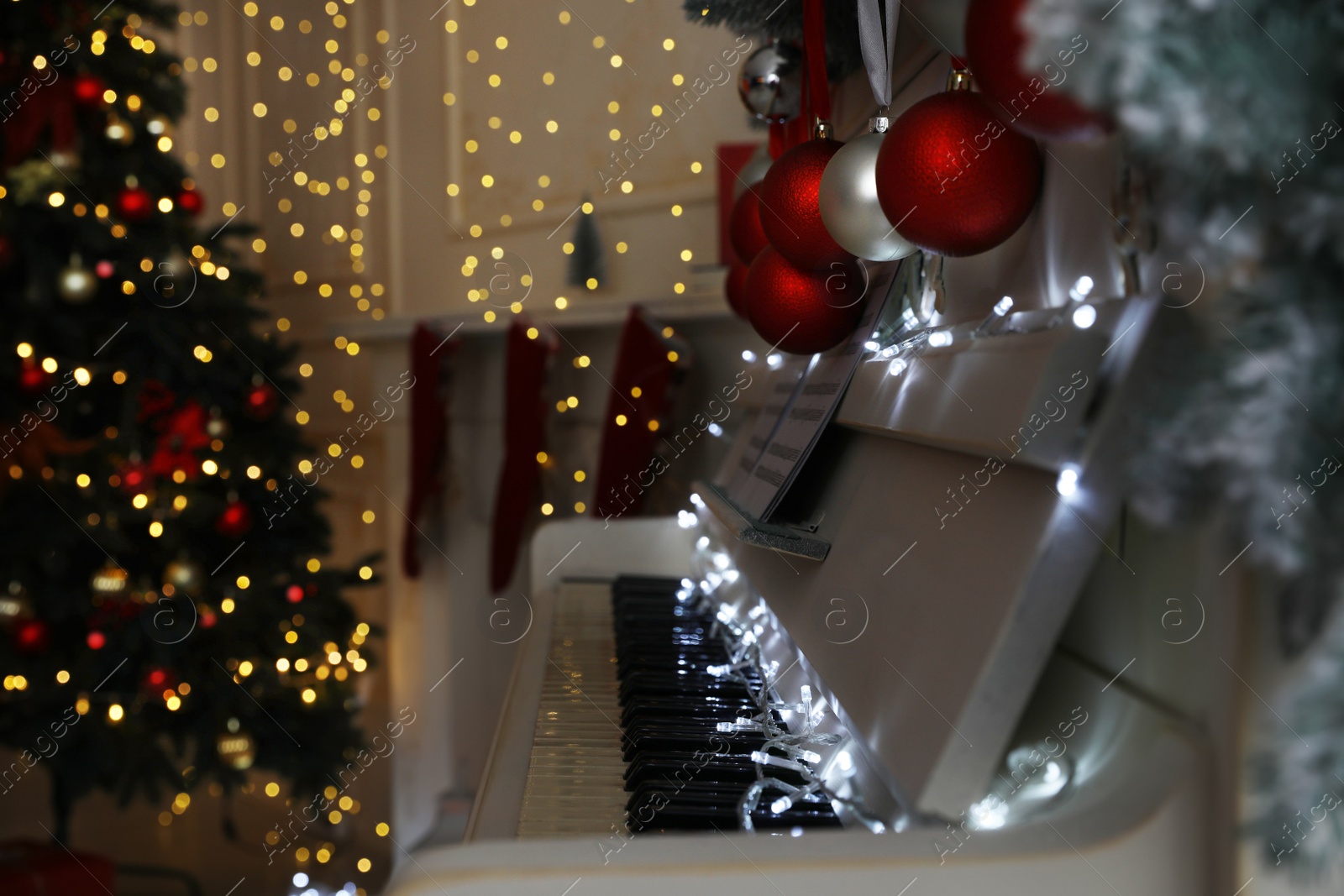 White piano with fairy lights and baubles indoors, space for text. Christmas music Photo of White piano with fairy lights and baubles indoors, space for text. Christmas music