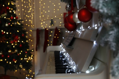 White piano with fairy lights and baubles indoors, space for text. Christmas music Photo of White piano with fairy lights and baubles indoors, space for text. Christmas music