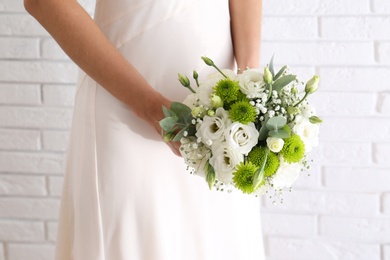 Bride holding beautiful bouquet with Eustoma flowers near brick wall, closeup Photo of Bride holding beautiful bouquet with Eustoma flowers near brick wall, closeup