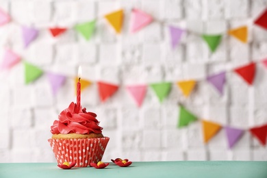 Birthday cupcake with candle against blurred background Photo of Birthday cupcake with candle against blurred background