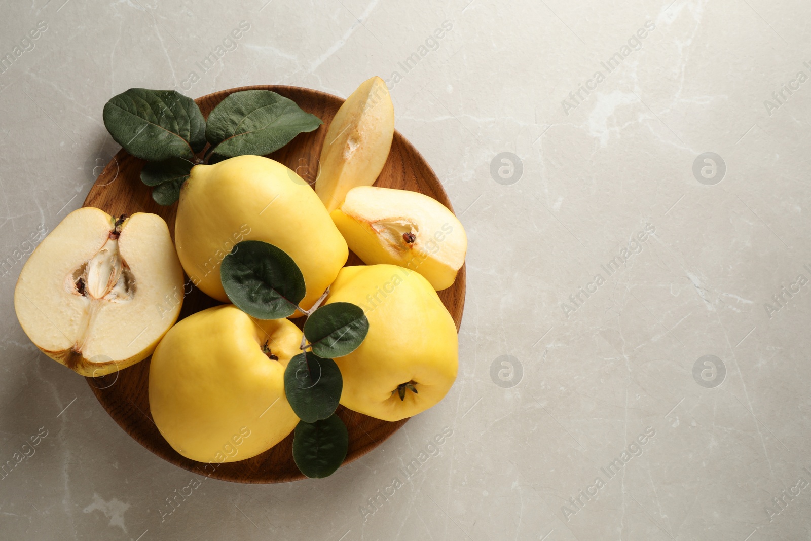 Fresh ripe organic quinces with leaves on light table, top view. Space for text Photo of Fresh ripe organic quinces with leaves on light table, top view. Space for text
