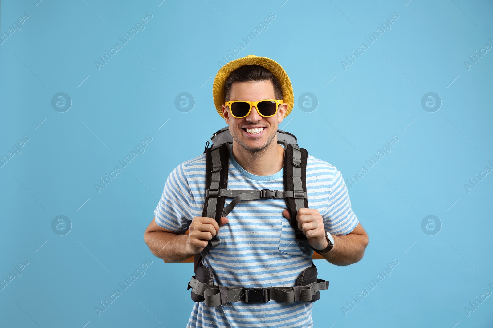 Photo of Male tourist with travel backpack on turquoise background