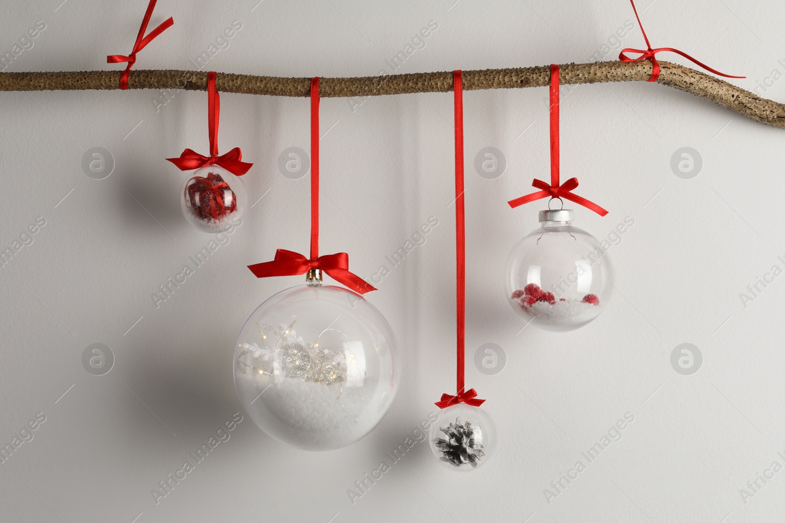 Decorative snow globes hanging on grey background Photo of Decorative snow globes hanging on grey background
