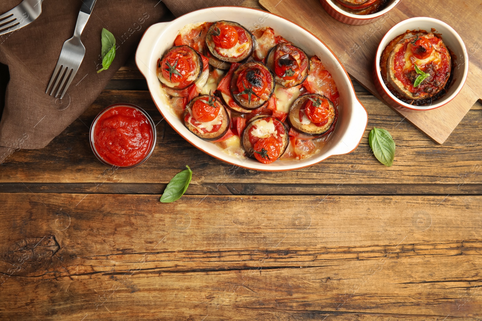 Baked eggplant with tomatoes, cheese and basil served on wooden table, flat lay. Space for text Photo of Baked eggplant with tomatoes, cheese and basil served on wooden table, flat lay. Space for text