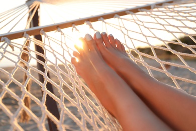 Young woman relaxing in hammock on beach at sunset, closeup Photo of Young woman relaxing in hammock on beach at sunset, closeup