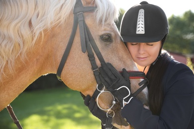 Young woman in horse riding suit and her beautiful pet outdoors on sunny day Photo of Young woman in horse riding suit and her beautiful pet outdoors on sunny day