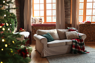 Festive interior with comfortable sofa and decorated Christmas tree Photo of Festive interior with comfortable sofa and decorated Christmas tree