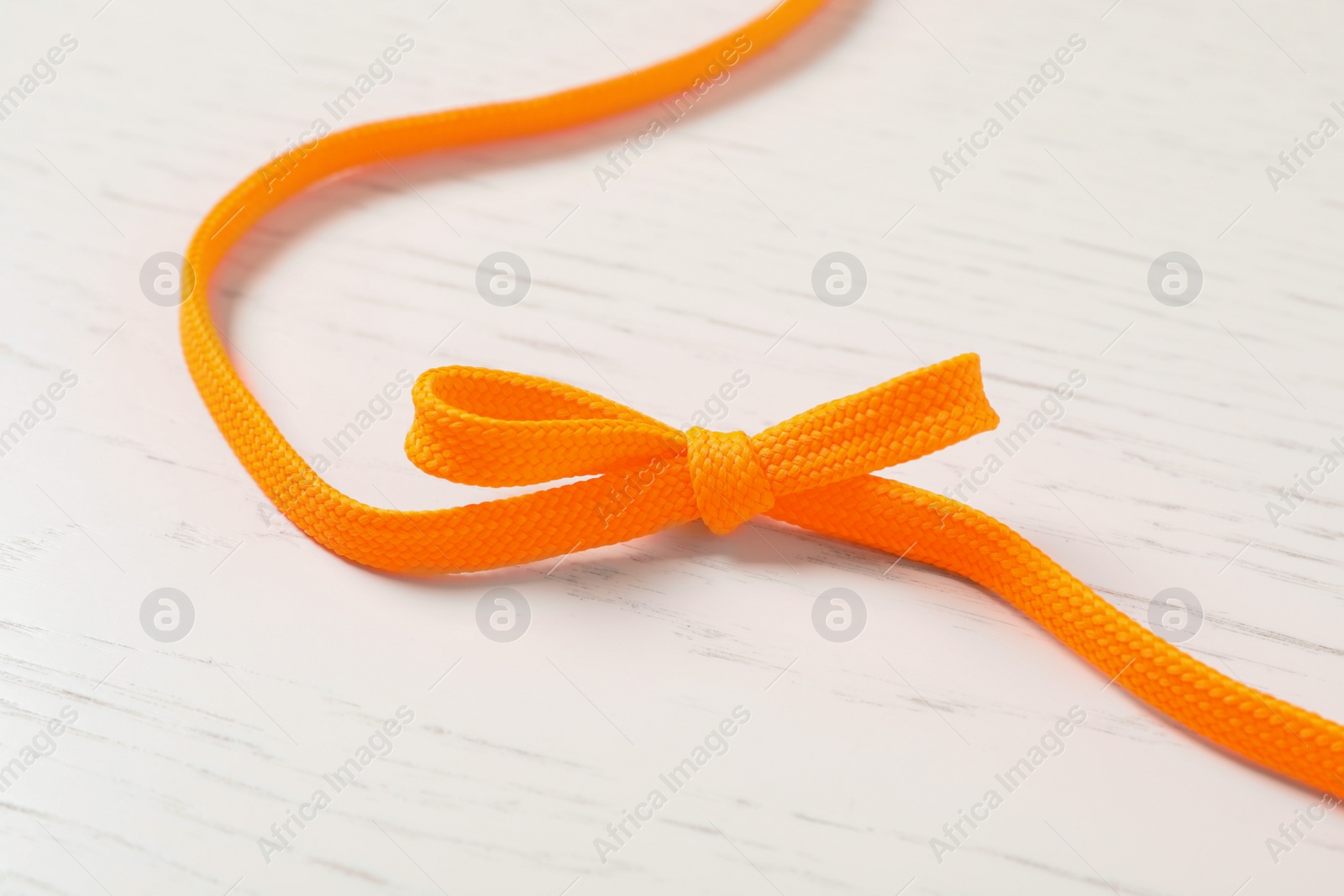 Orange shoelace on white wooden background. Stylish accessory Photo of Orange shoelace on white wooden background. Stylish accessory