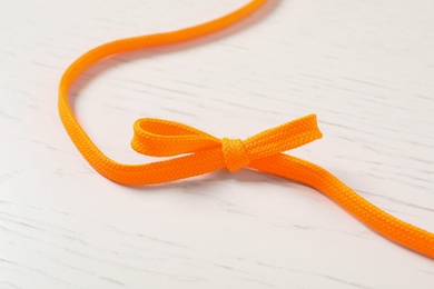 Orange shoelace on white wooden background. Stylish accessory Photo of Orange shoelace on white wooden background. Stylish accessory