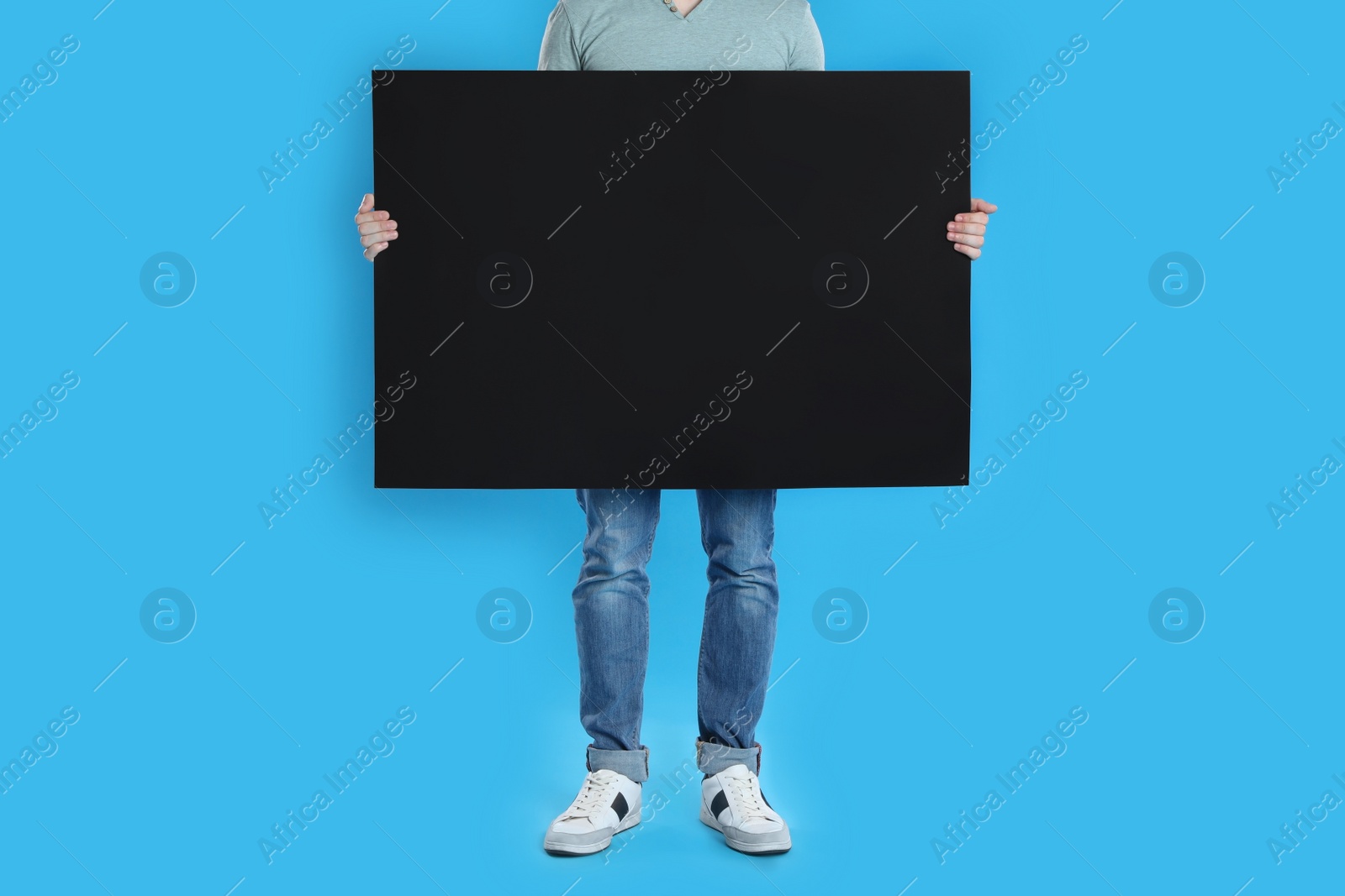 Man holding blank poster on blue background, closeup Photo of Man holding blank poster on blue background, closeup