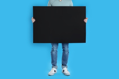 Man holding blank poster on blue background, closeup Photo of Man holding blank poster on blue background, closeup