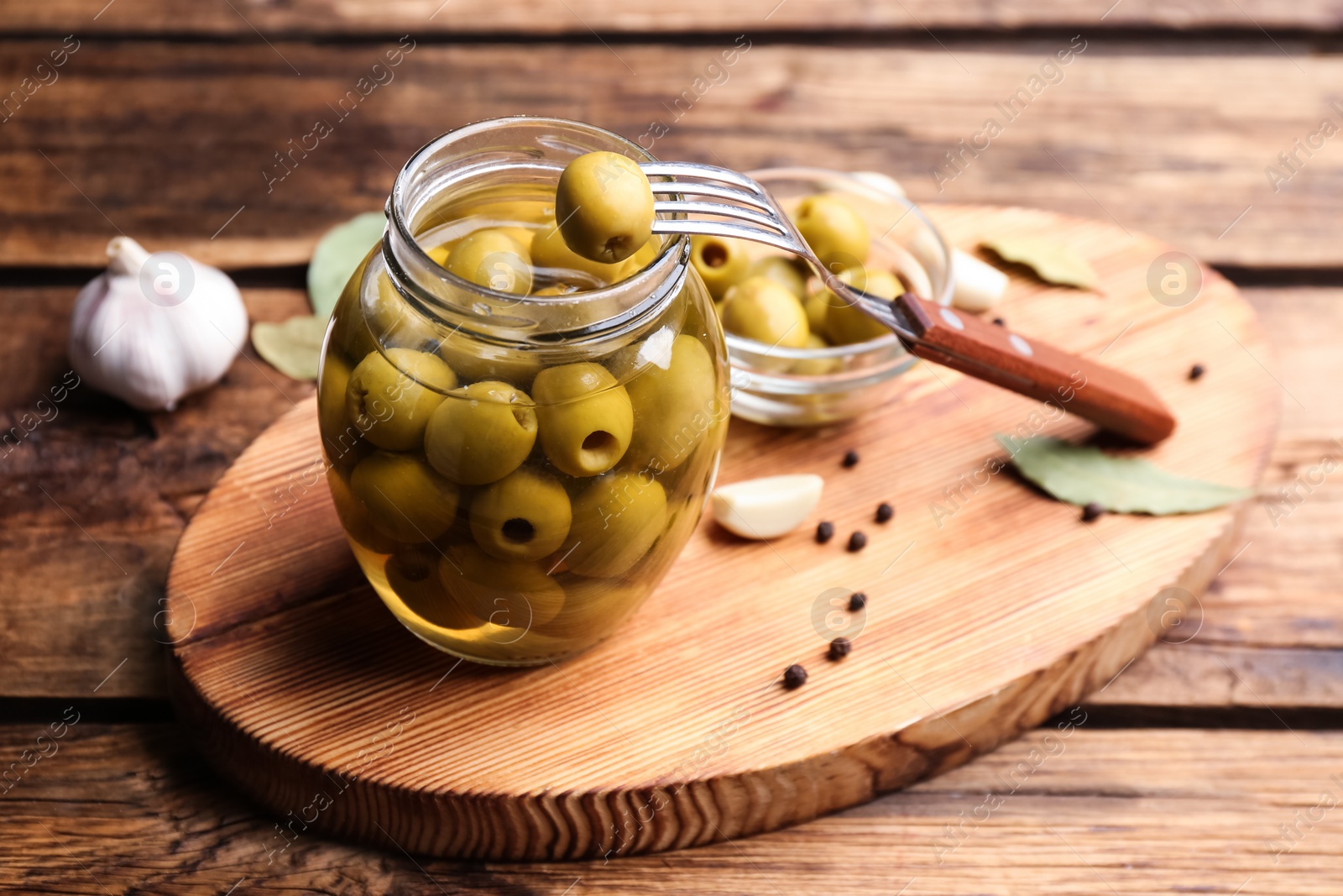 Glass jar of pickled olives on wooden table Photo of Glass jar of pickled olives on wooden table