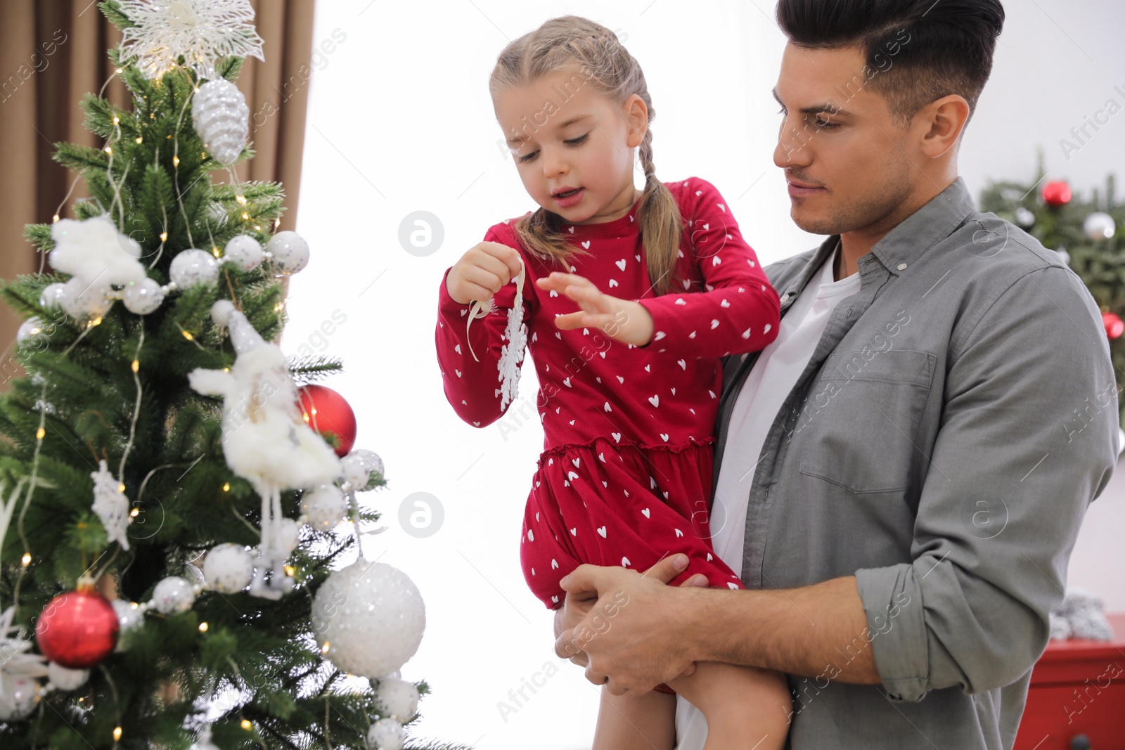Father with his cute daughter decorating Christmas tree together at home Photo of Father with his cute daughter decorating Christmas tree together at home