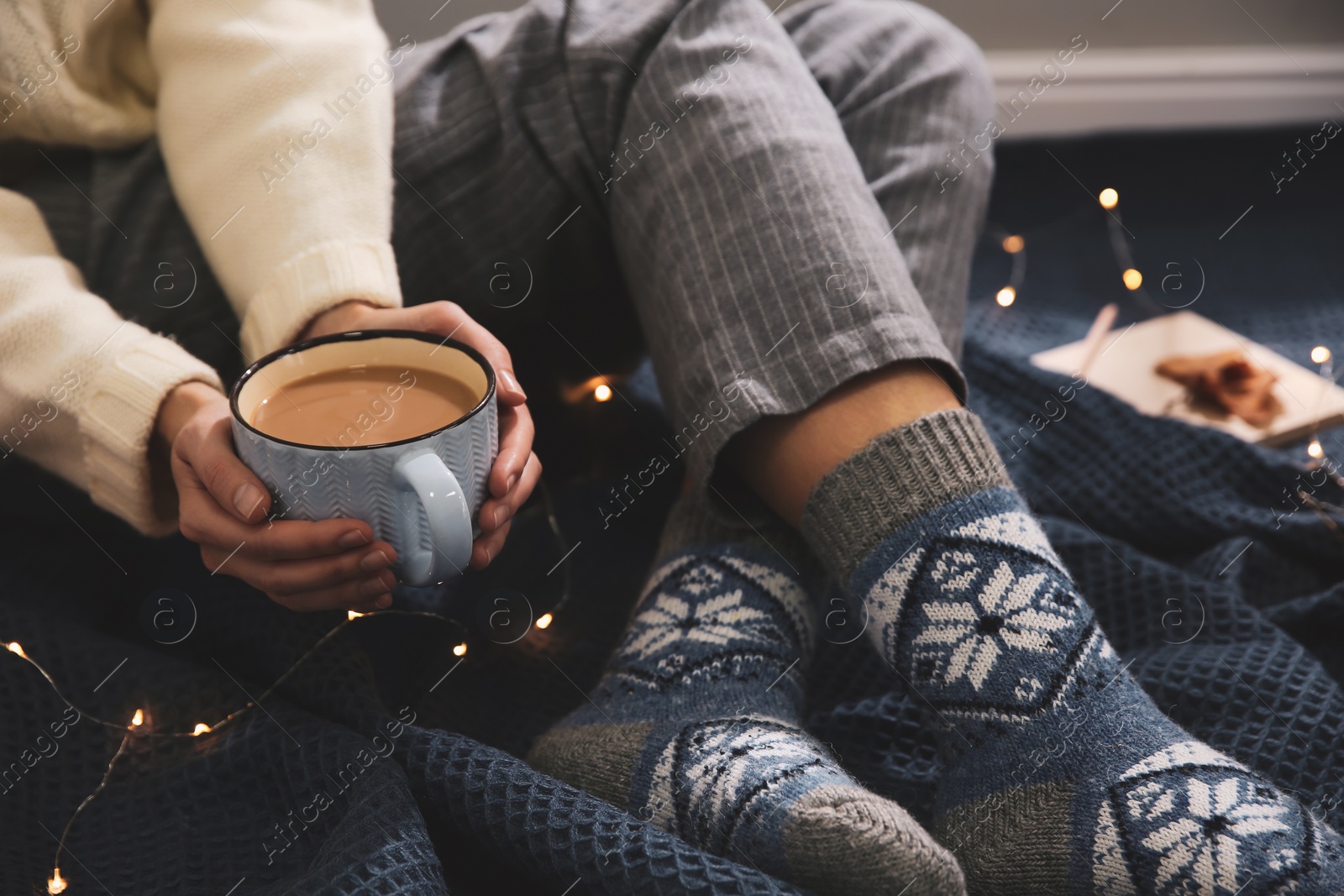 Woman relaxing with cup of hot winter drink on warm plaid indoors, closeup. Cozy season Photo of Woman relaxing with cup of hot winter drink on warm plaid indoors, closeup. Cozy season