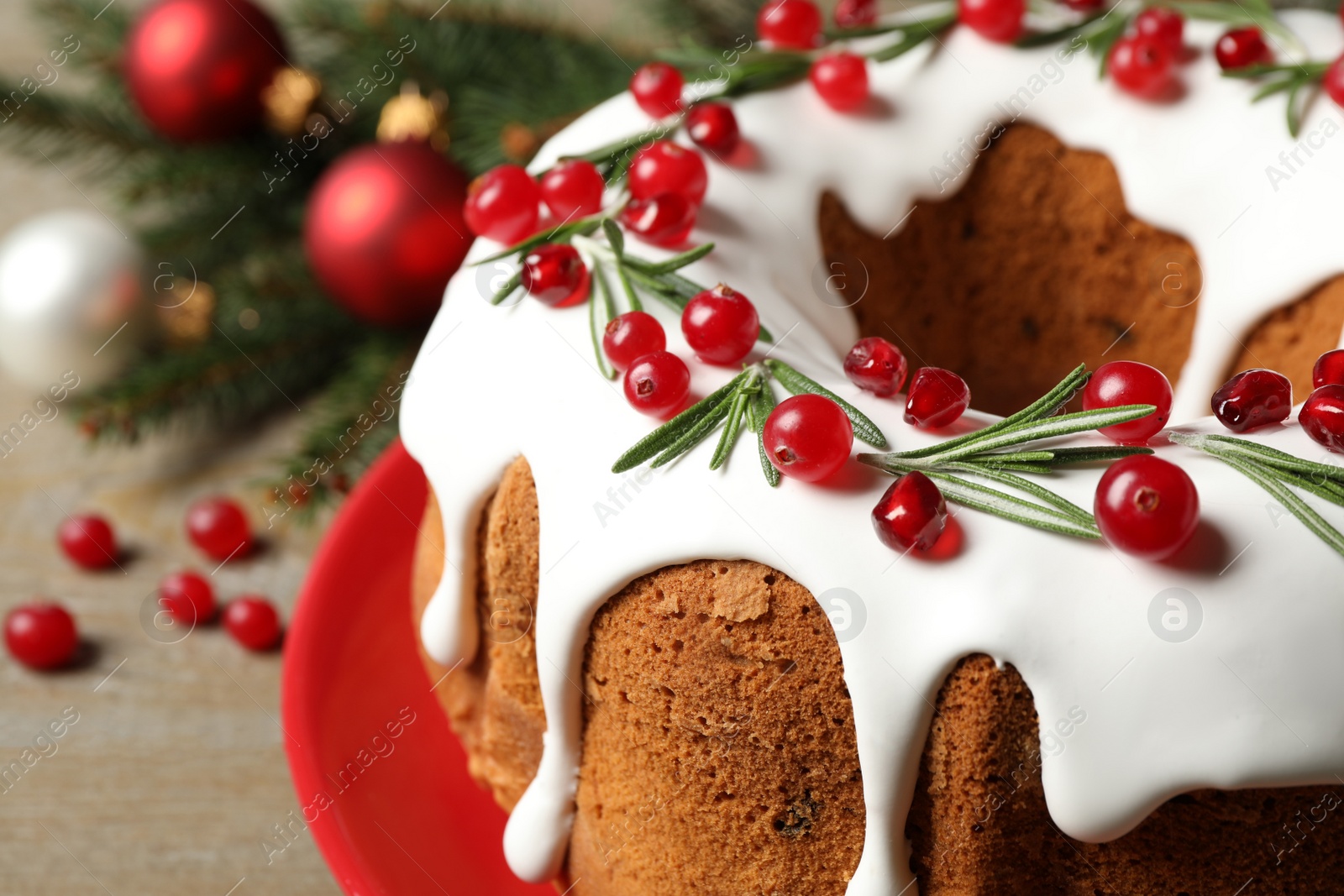 Traditional Christmas cake decorated with glaze, pomegranate seeds, cranberries and rosemary on table, closeup Photo of Traditional Christmas cake decorated with glaze, pomegranate seeds, cranberries and rosemary on table, closeup
