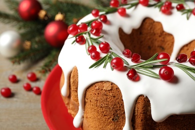 Traditional Christmas cake decorated with glaze, pomegranate seeds, cranberries and rosemary on table, closeup Photo of Traditional Christmas cake decorated with glaze, pomegranate seeds, cranberries and rosemary on table, closeup