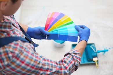 Male decorator holding color palette samples indoors Photo of Male decorator holding color palette samples indoors