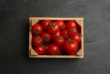 Fresh ripe cherry tomatoes in wooden crate on black table, top view Photo of Fresh ripe cherry tomatoes in wooden crate on black table, top view