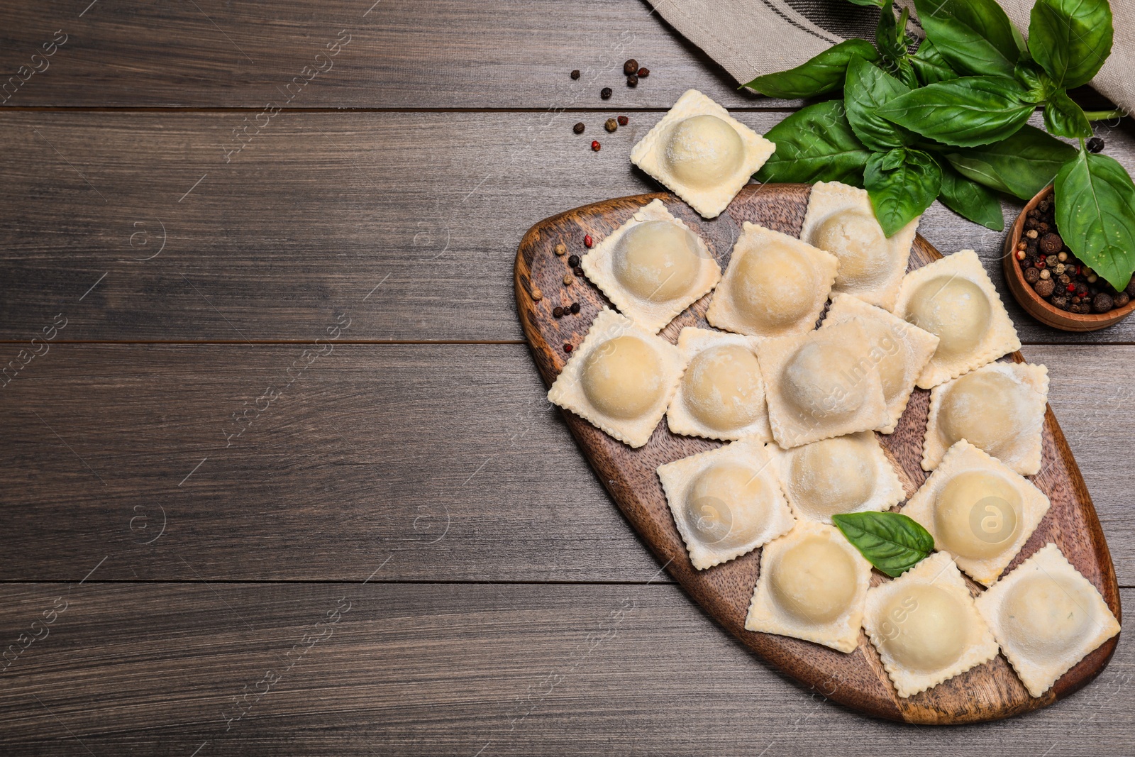 Uncooked ravioli, basil and peppercorns on wooden table, flat lay. Space for text Photo of Uncooked ravioli, basil and peppercorns on wooden table, flat lay. Space for text