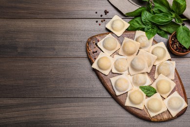 Uncooked ravioli, basil and peppercorns on wooden table, flat lay. Space for text Photo of Uncooked ravioli, basil and peppercorns on wooden table, flat lay. Space for text