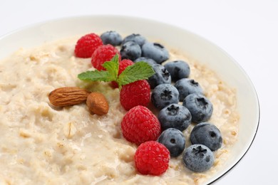 Tasty oatmeal porridge with raspberries, blueberries and almond nuts in bowl on white background, closeup Photo of Tasty oatmeal porridge with raspberries, blueberries and almond nuts in bowl on white background, closeup