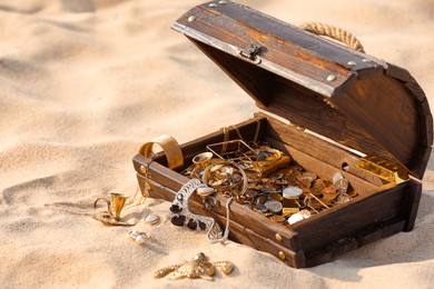 Open wooden treasure chest on sand, space for text Photo of Open wooden treasure chest on sand, space for text
