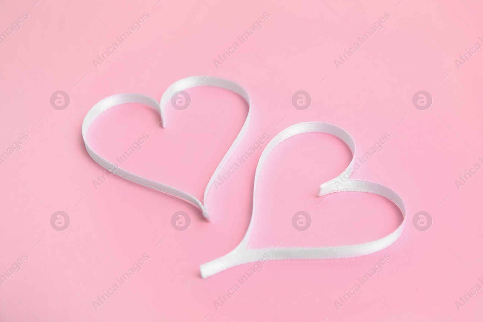 Hearts made of white ribbon on pink background. Valentine's day celebration Photo of Hearts made of white ribbon on pink background. Valentine's day celebration