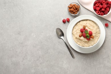 Tasty oatmeal porridge with raspberries and almond nuts served on light grey table, flat lay. Space for text Photo of Tasty oatmeal porridge with raspberries and almond nuts served on light grey table, flat lay. Space for text