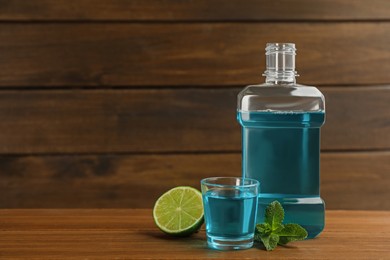 Mouthwash, mint and lime on wooden table, space for text Photo of Mouthwash, mint and lime on wooden table, space for text