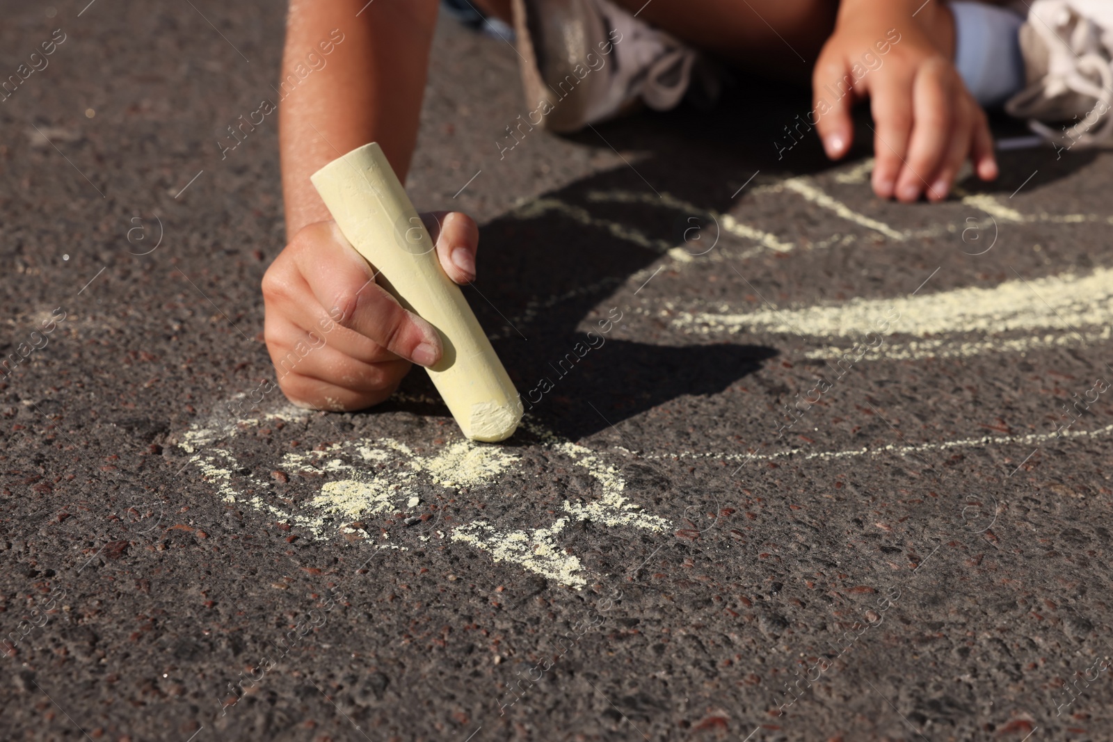 Little child drawing cat with colorful chalk on asphalt, closeup Photo of Little child drawing cat with colorful chalk on asphalt, closeup