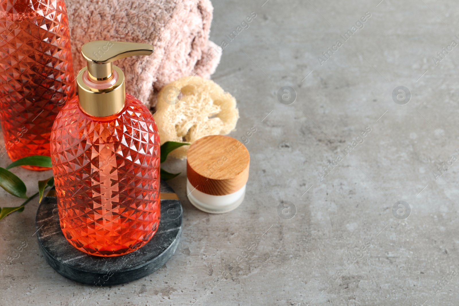 Stylish dispenser with liquid soap and other bathroom amenities on grey table, space for text Photo of Stylish dispenser with liquid soap and other bathroom amenities on grey table, space for text