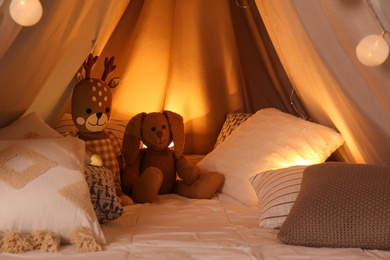 Play tent with toys and pillows indoors, closeup. Modern children's room interior Photo of Play tent with toys and pillows indoors, closeup. Modern children's room interior