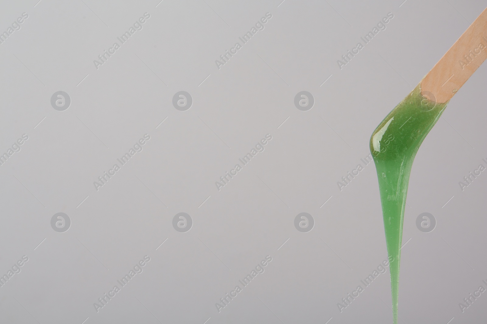 Wooden spatula with hot depilatory wax on light grey background. Space for text Photo of Wooden spatula with hot depilatory wax on light grey background. Space for text