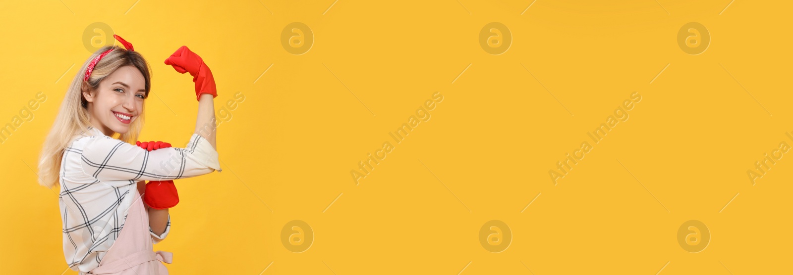 Young housewife in gloves on yellow background. Space for text Photo of Young housewife in gloves on yellow background. Space for text