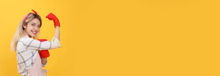 Young housewife in gloves on yellow background. Space for text Photo of Young housewife in gloves on yellow background. Space for text