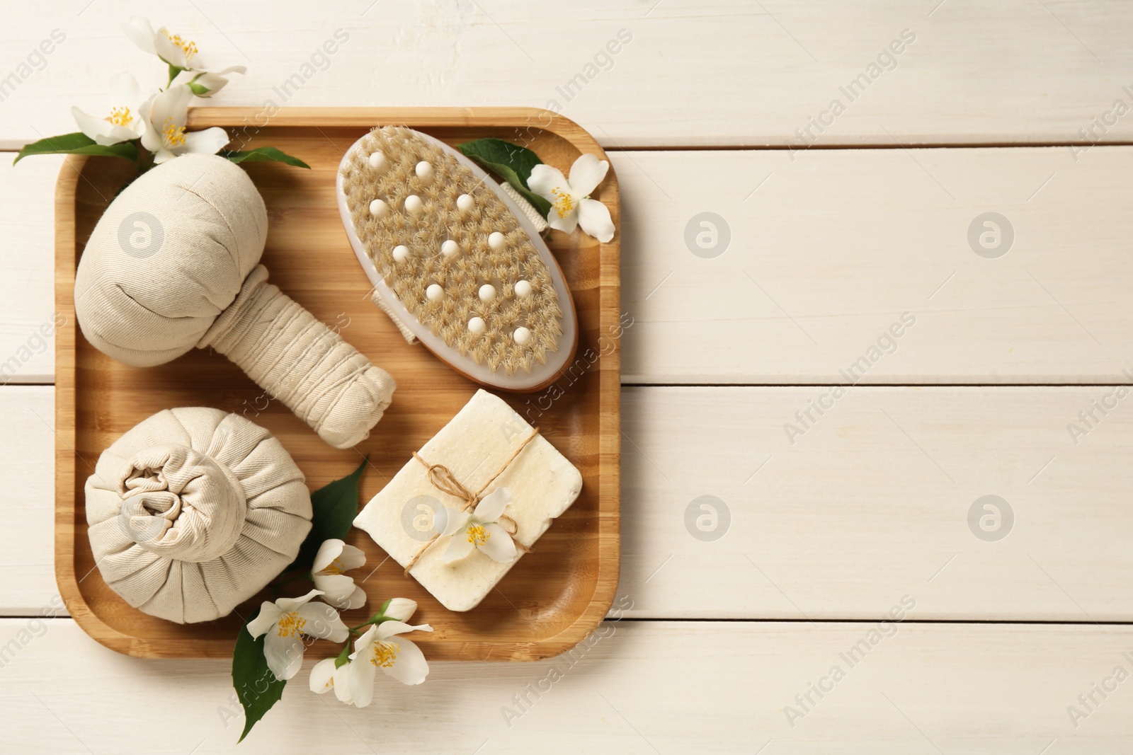 Beautiful jasmine flowers, herbal bags, brush and soap bar on white wooden table, top view. Space for text Photo of Beautiful jasmine flowers, herbal bags, brush and soap bar on white wooden table, top view. Space for text