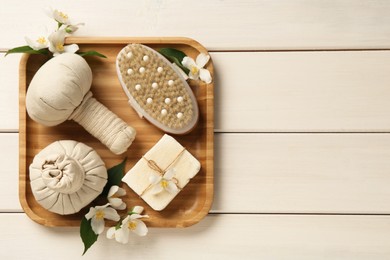 Beautiful jasmine flowers, herbal bags, brush and soap bar on white wooden table, top view. Space for text Photo of Beautiful jasmine flowers, herbal bags, brush and soap bar on white wooden table, top view. Space for text