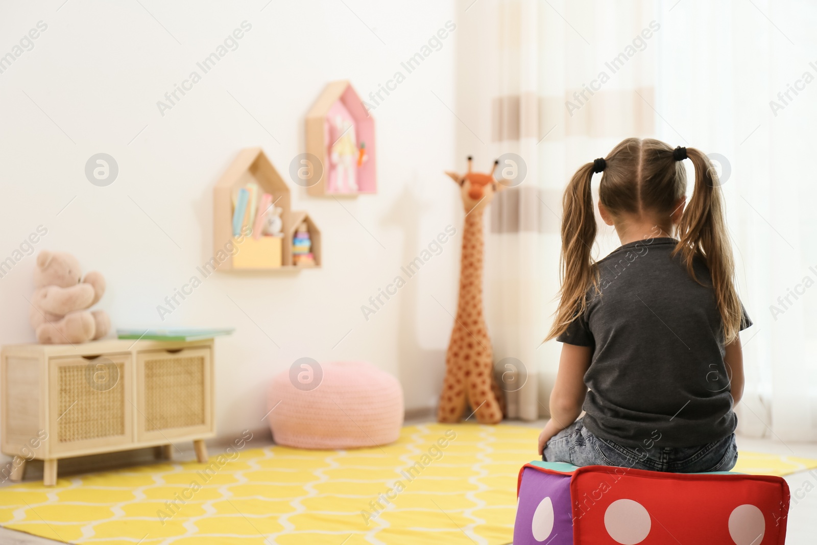 Photo of Lonely little girl at home, back view. Autism concept