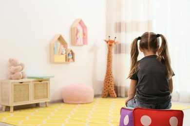 Lonely little girl at home, back view. Autism concept Photo of Lonely little girl at home, back view. Autism concept